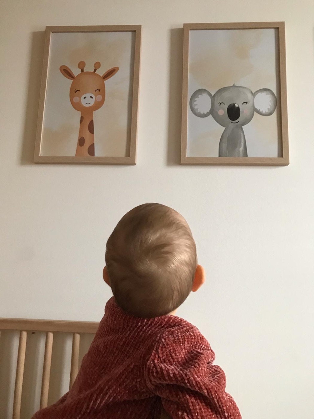 Baby betrachtet die Les Petits Tierbilder im Kinderzimmer